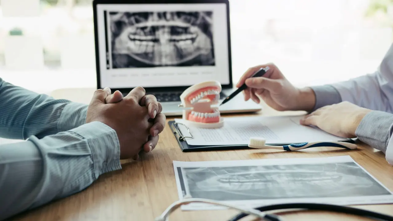 two dentists look at a dental x-ray and discuss potential challenges for the patient