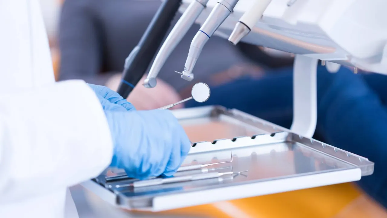 a close-up of a dentist’s hands and dental equipment