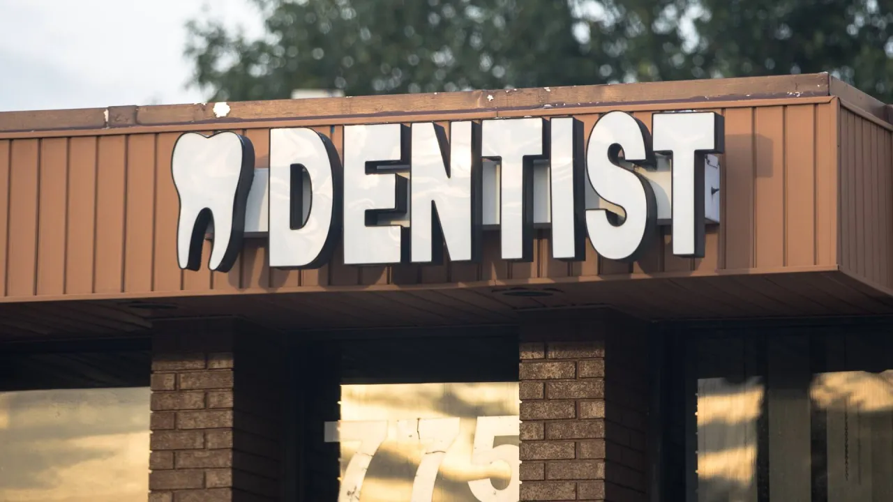the front of a dentist’s office practice location, showing a building with a sign saying dentist