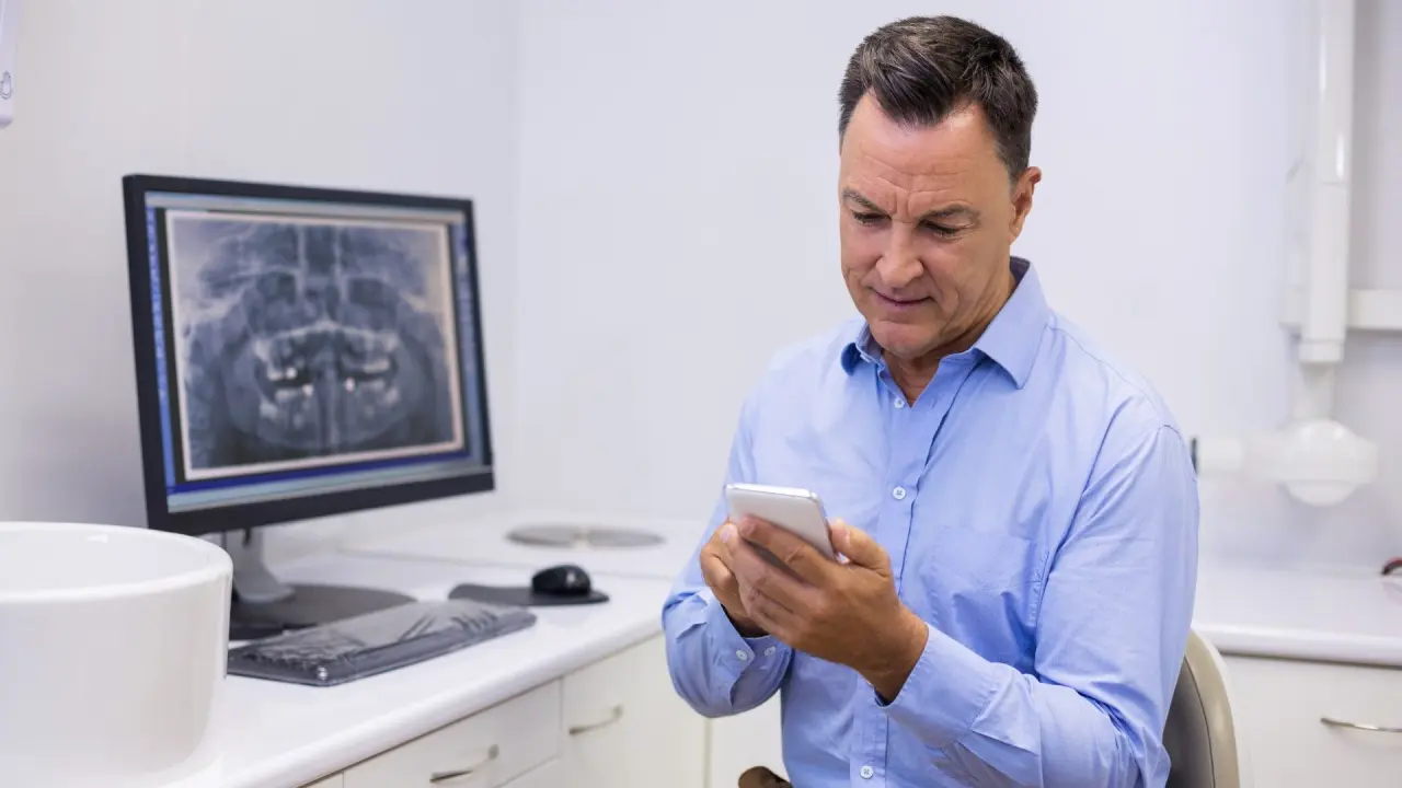 a dentist uses a mobile phone to get help buying or selling a dental practice