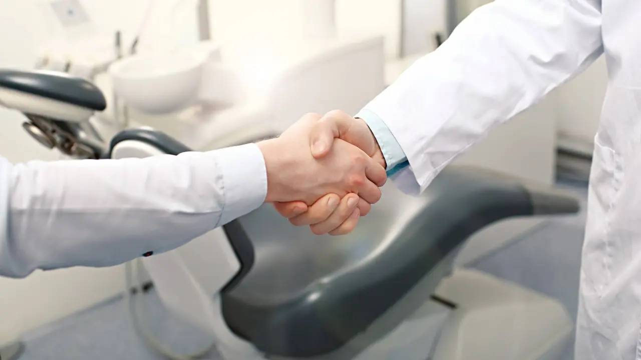 a dentist shakes hands with other dentist to get through closing